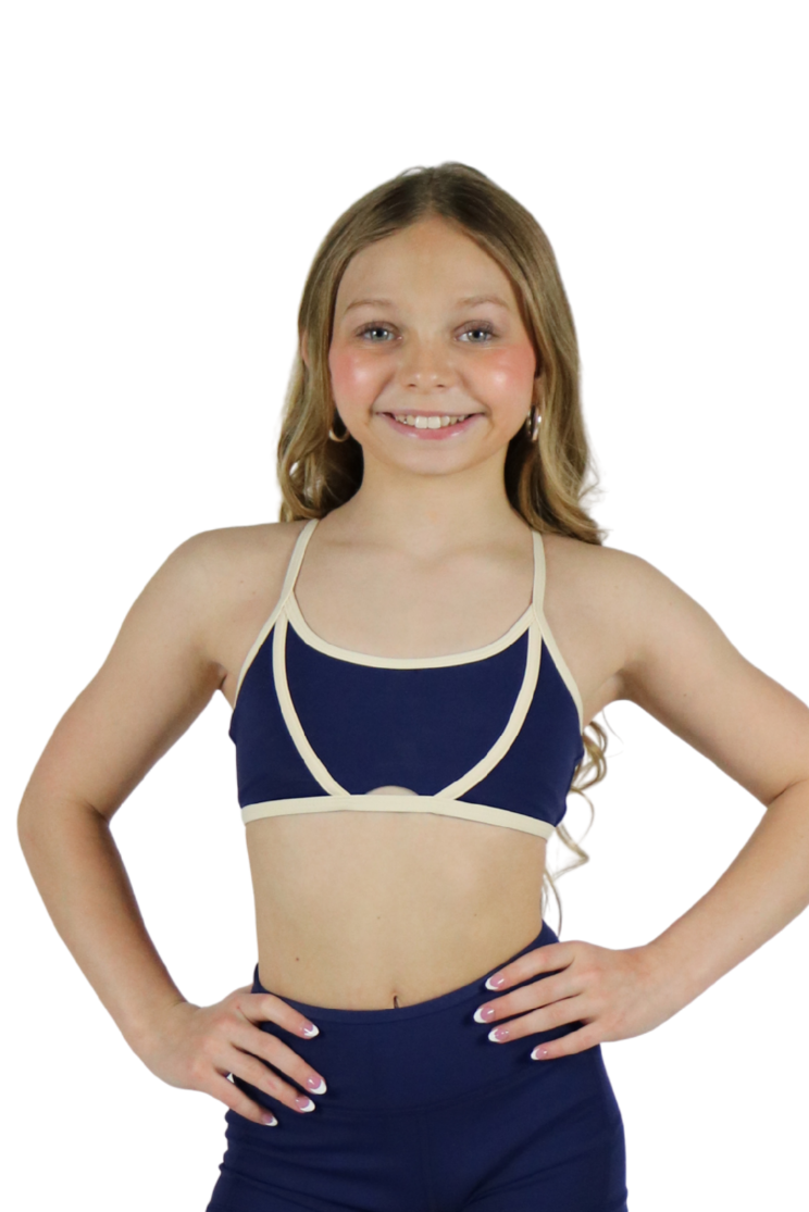 Young girl wearing a navy blue swimsuit with a white top on a white background
