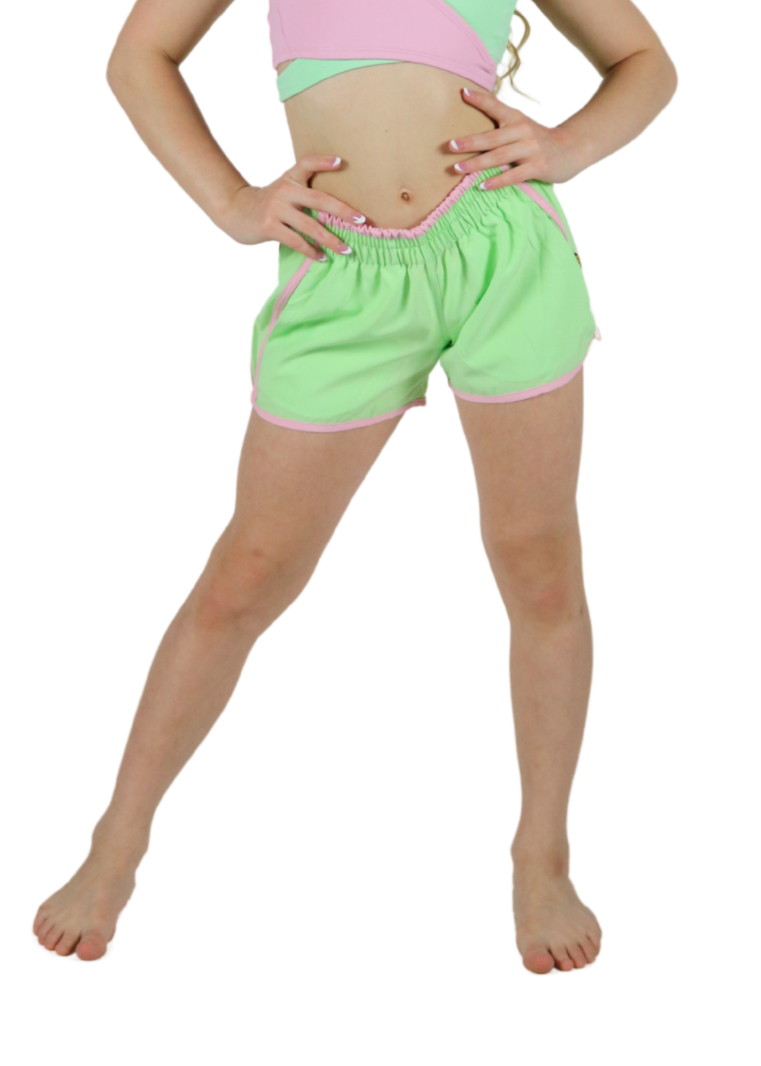 Young girl wearing a pink and green crop top with matching shorts on a white background
