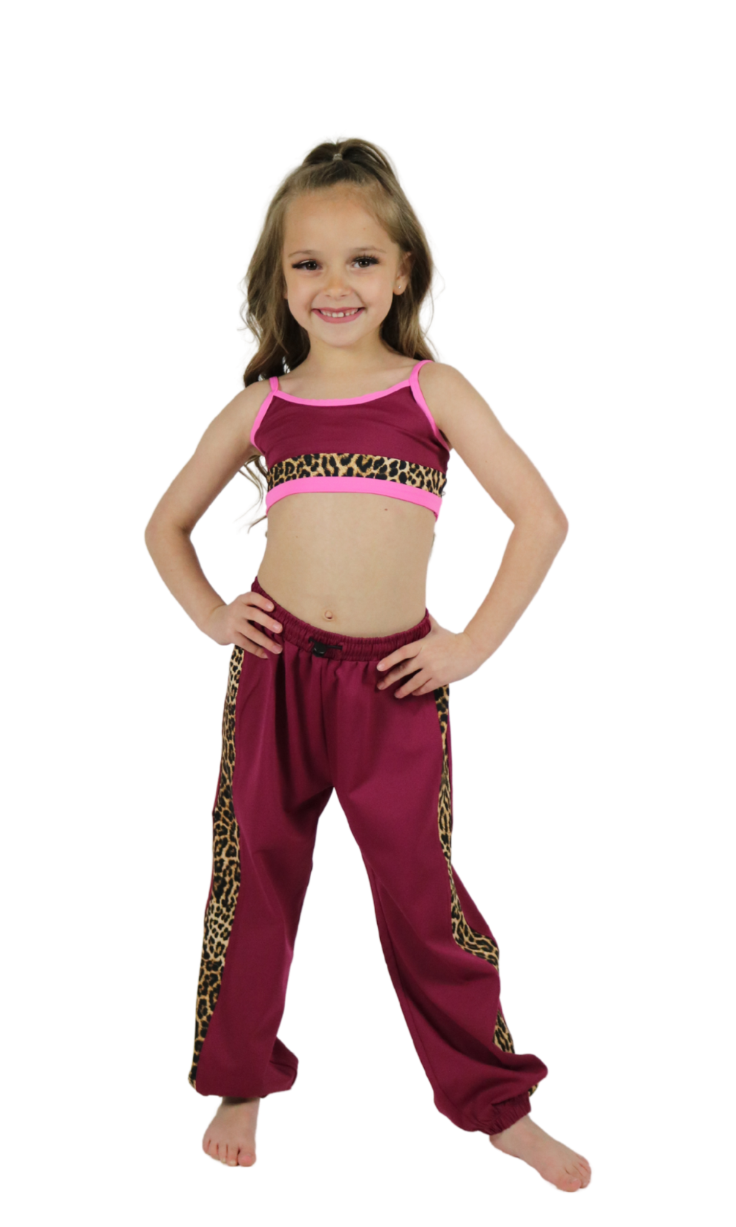 Young girl wearing a pink top and maroon pants with leopard print trim on a white background