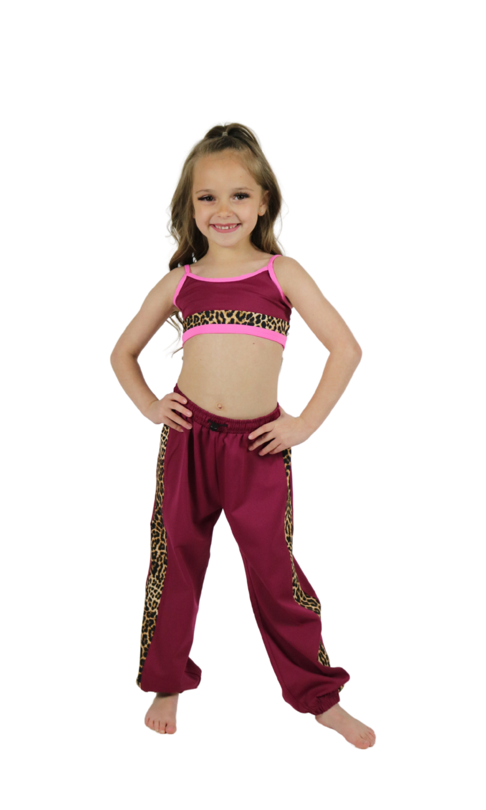 Young girl wearing a pink top and maroon pants with leopard print trim on a white background