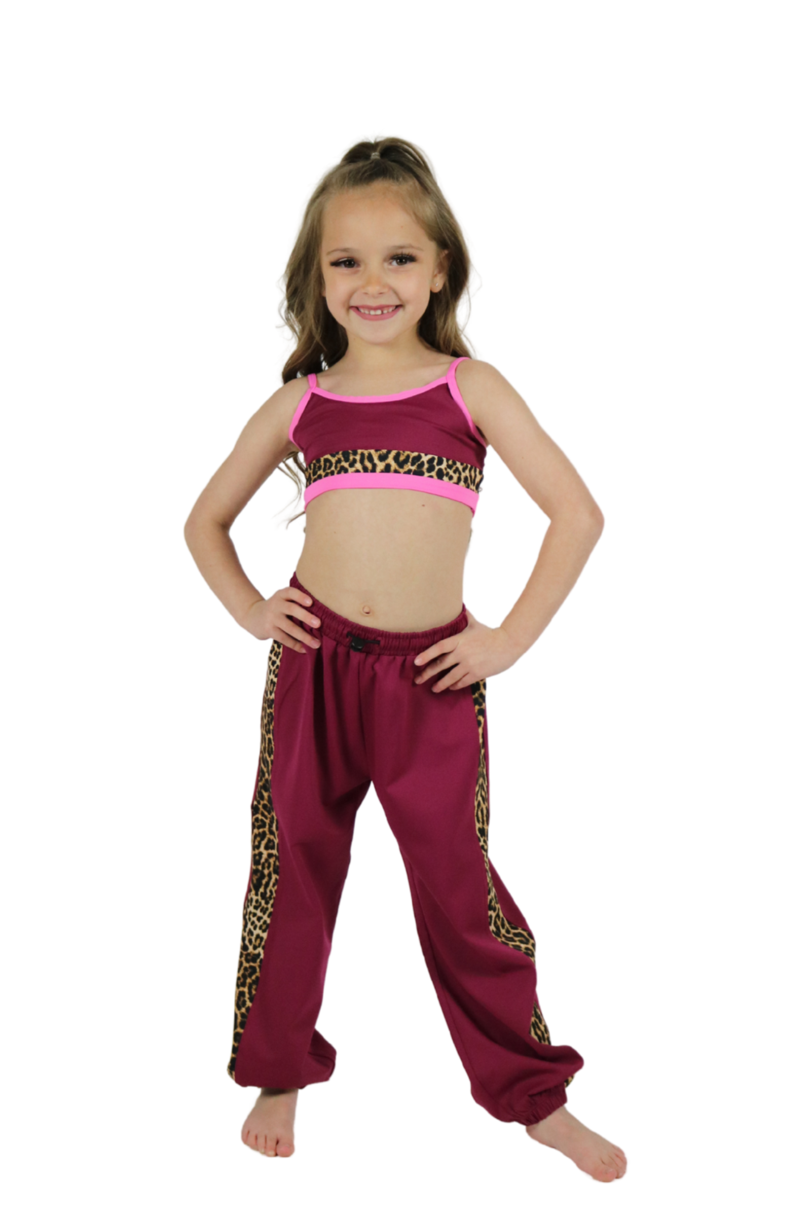 Young girl wearing a pink top and maroon pants with leopard print trim on a white background