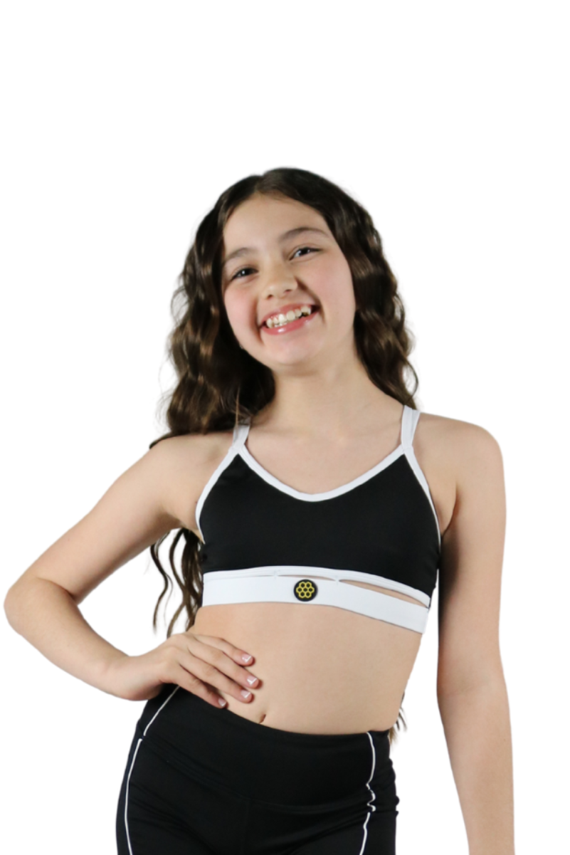 Young girl wearing a black sports bra and shorts set on a white background