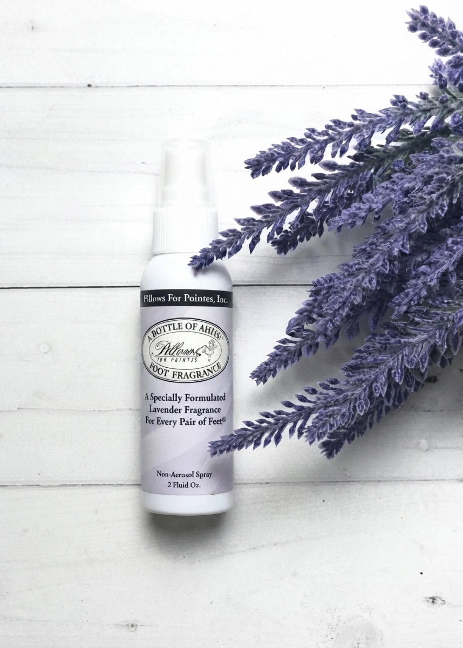 Pillows for Pointes Bottle of Ahhs! Lavender Foot Spray, lifestyle view showing 2 oz bottle beside lavender sprigs