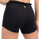 Honeycut Cabana Short in Black, back view showing nylon-spandex fabric, ruffled waistband and logo