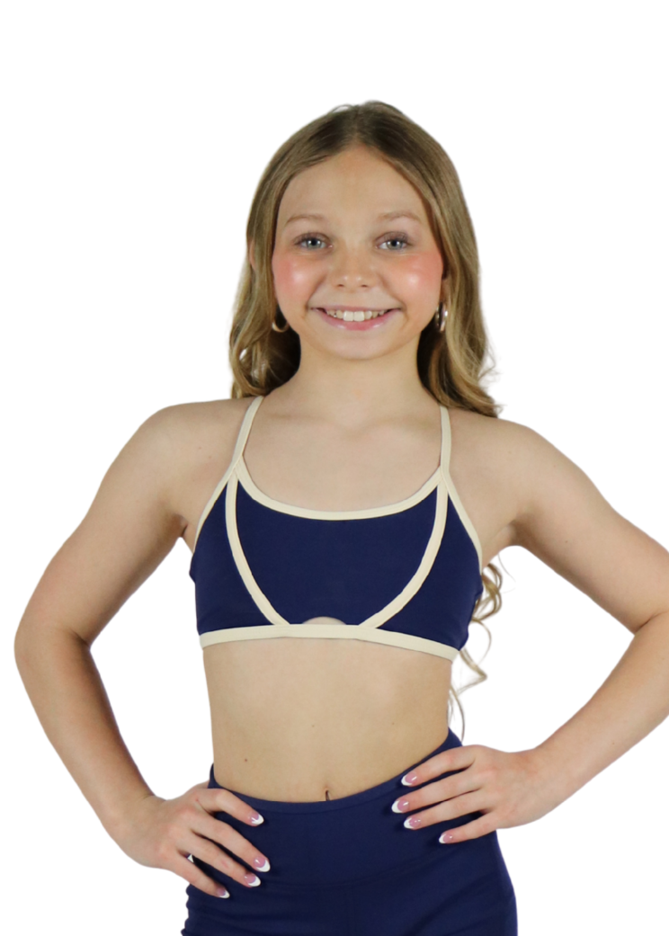 Young girl wearing a navy blue swimsuit with a white top on a white background