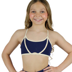 Young girl wearing a navy blue swimsuit with a white top on a white background