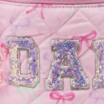 OMG Accessories Makeup Bow Pouch in Pink, detail view showing quilted bow-print exterior and zip closure