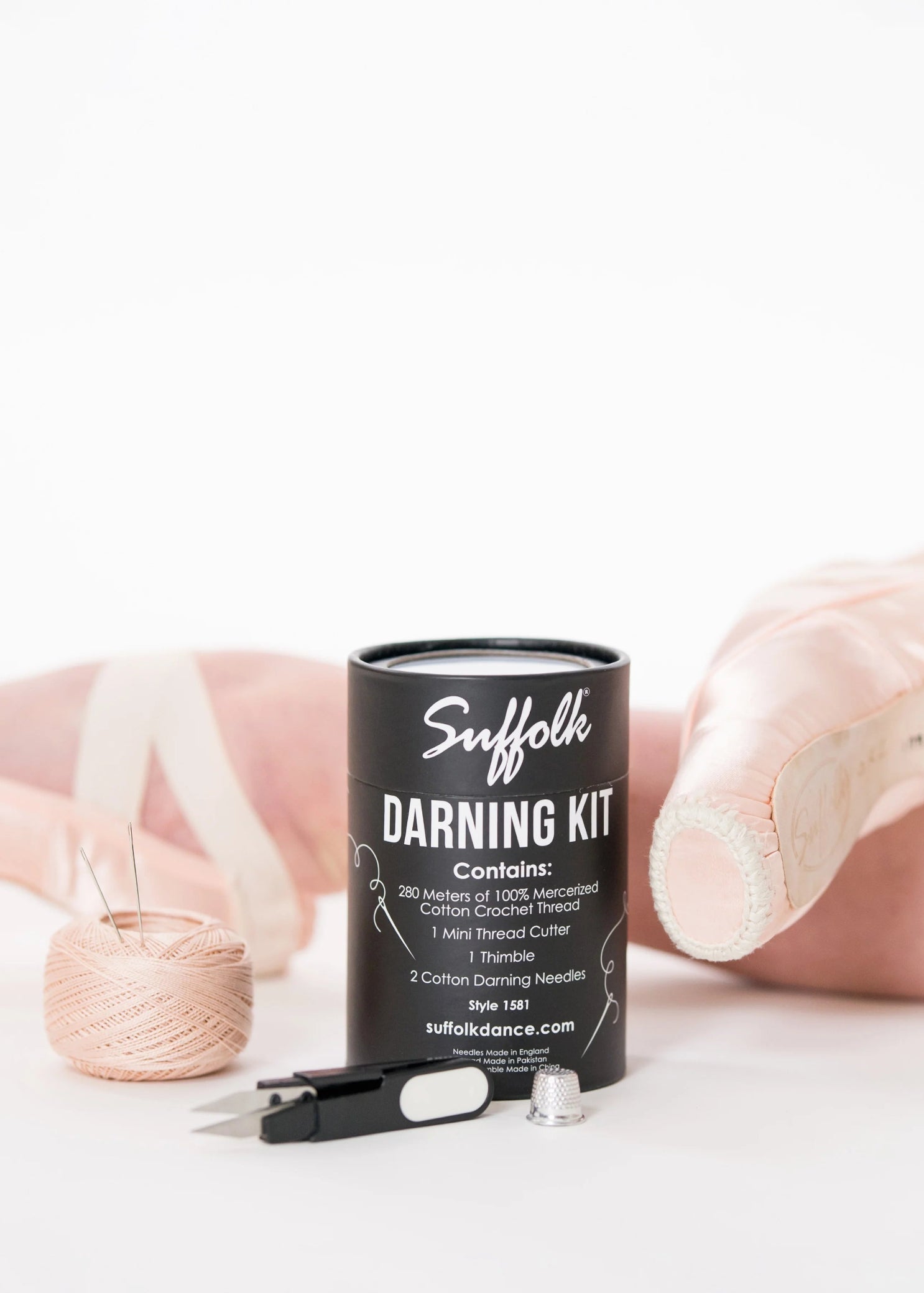 Suffolk Darning Sewing Kit in Pink, lifestyle view showing cotton thread, cutter and thimble beside pointe shoes
