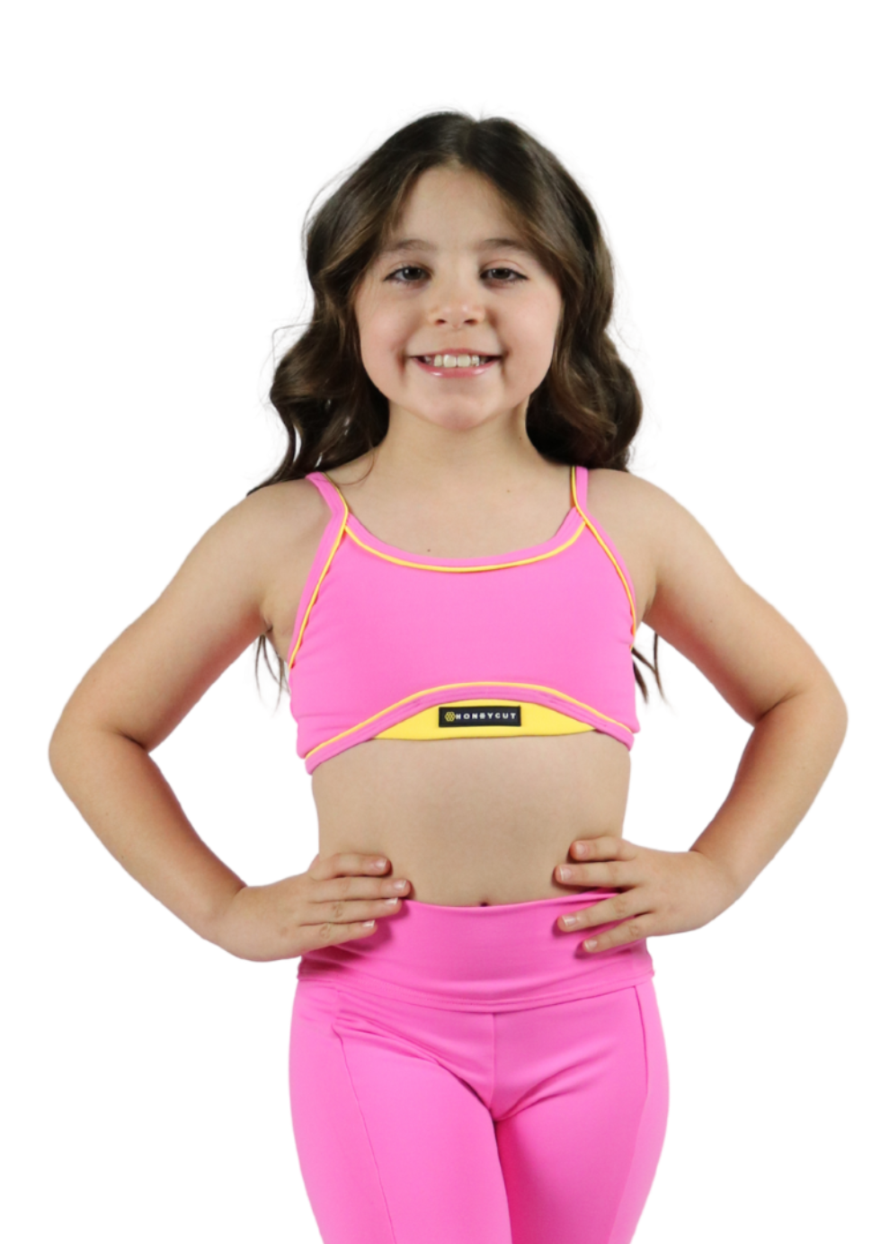 Young girl wearing a pink sports bra and leggings set on a white background