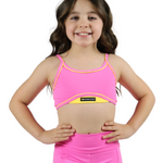 Young girl wearing a pink sports bra and leggings set on a white background