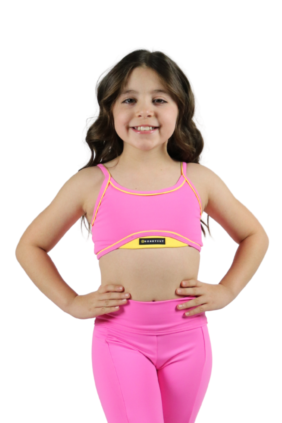 Young girl wearing a pink sports bra and leggings set on a white background