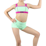 Young girl wearing a green and pink dance outfit on a white background