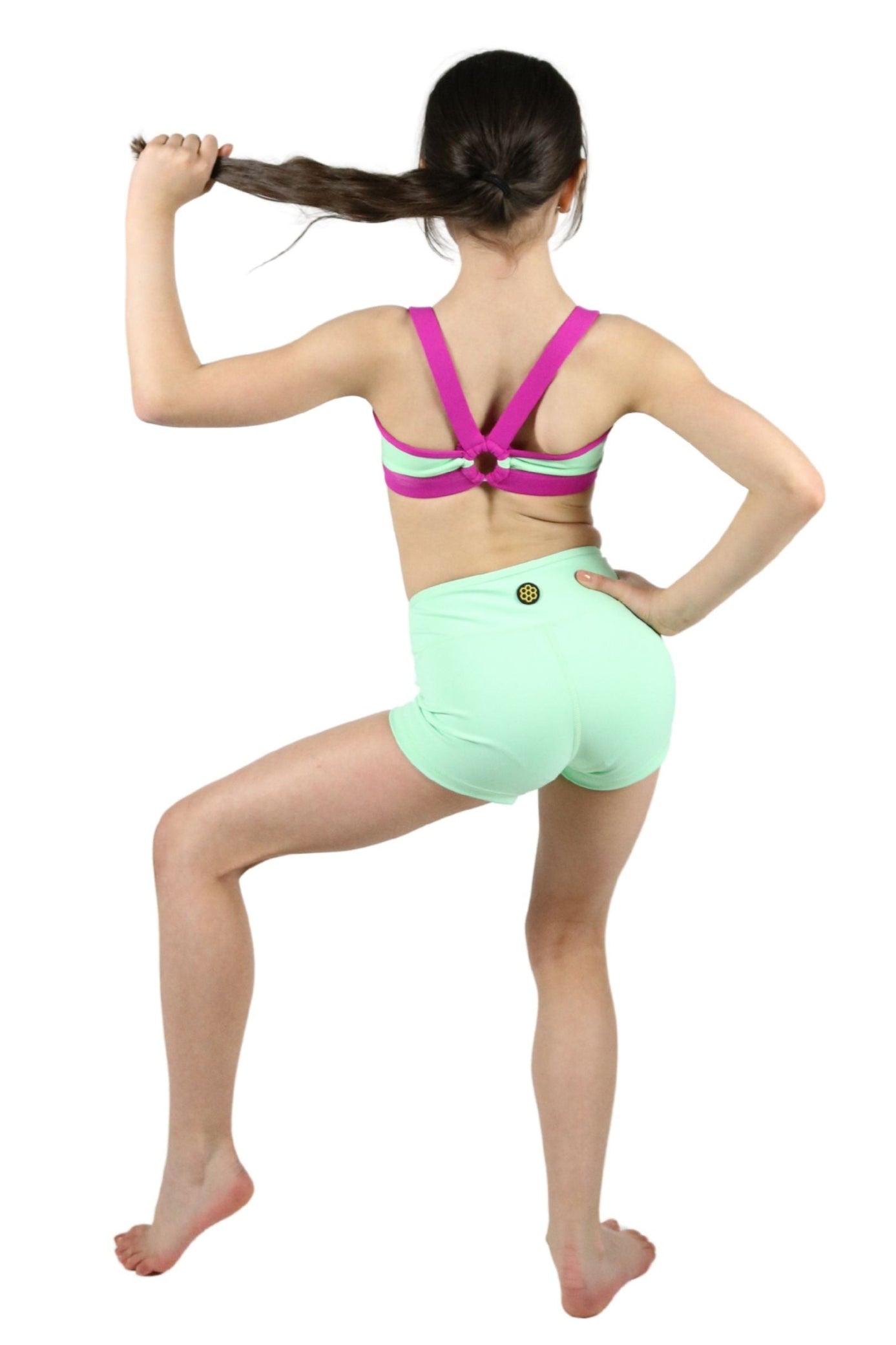 Person wearing a colorful sports bra and green shorts on a white background