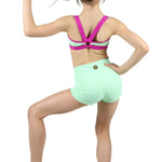 Person wearing a colorful sports bra and green shorts on a white background