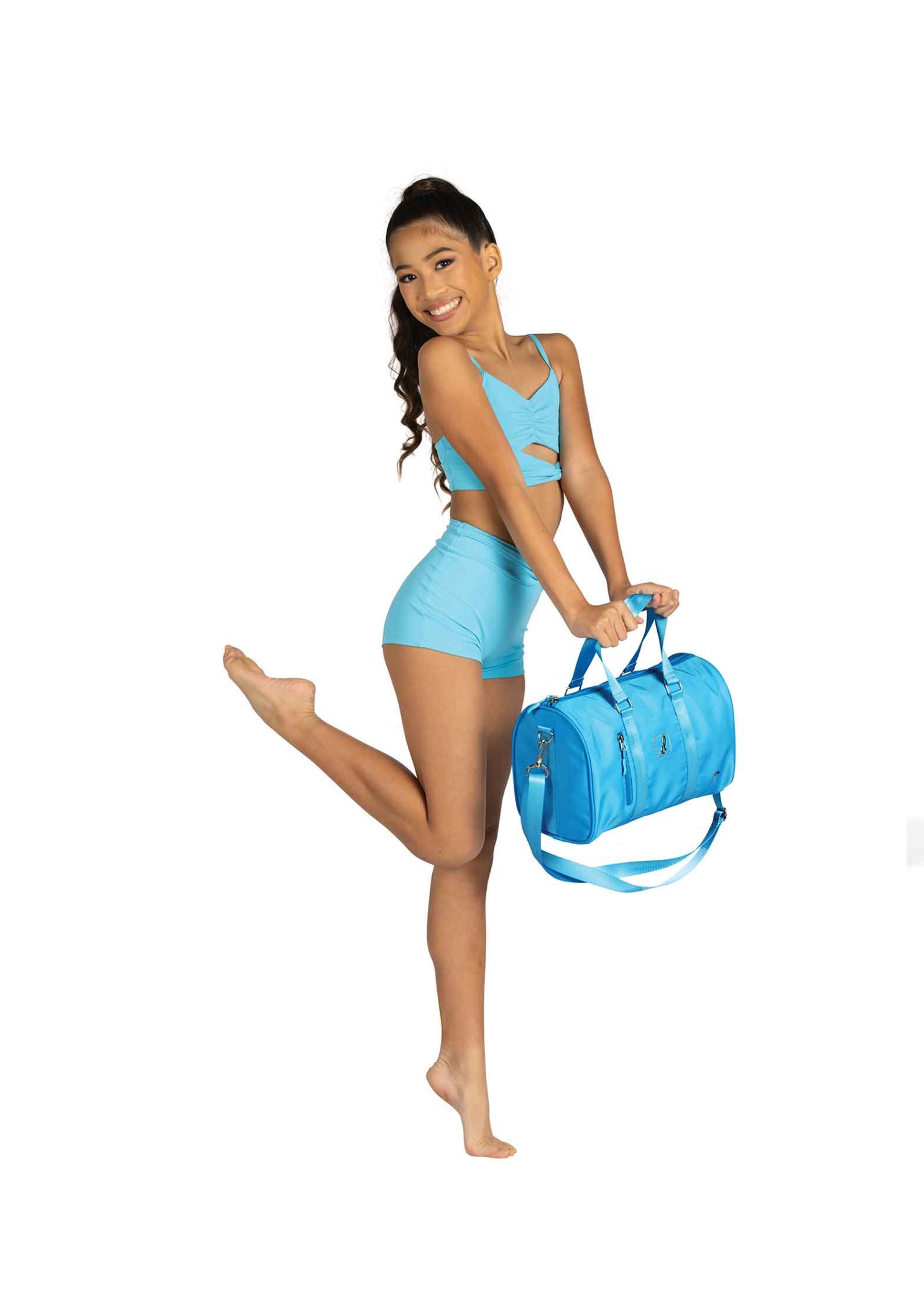 Danznmotion Jr Dance Duffel in Turquoise, lifestyle view showing front zip pocket, heart emblem, and logo badge
