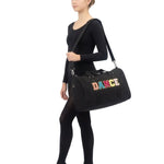 Dasha Designs Multi Dance Duffel in Black, lifestyle view showing chenille DANCE lettering and dual top handles