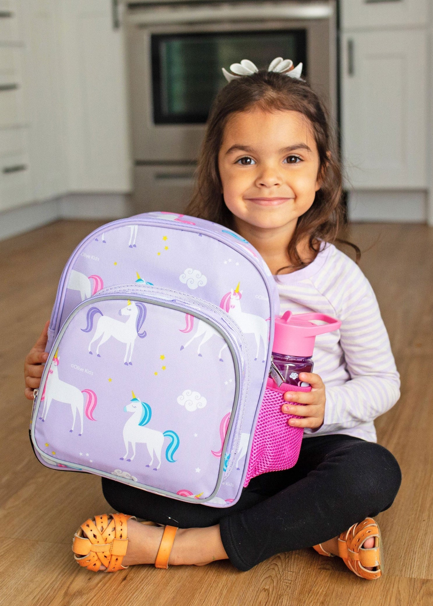 Wildkin Unicorn Backpack in Purple, lifestyle view showing unicorn print and water bottle in side mesh pocket