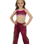 Young girl wearing a pink top and maroon pants with leopard print trim on a white background