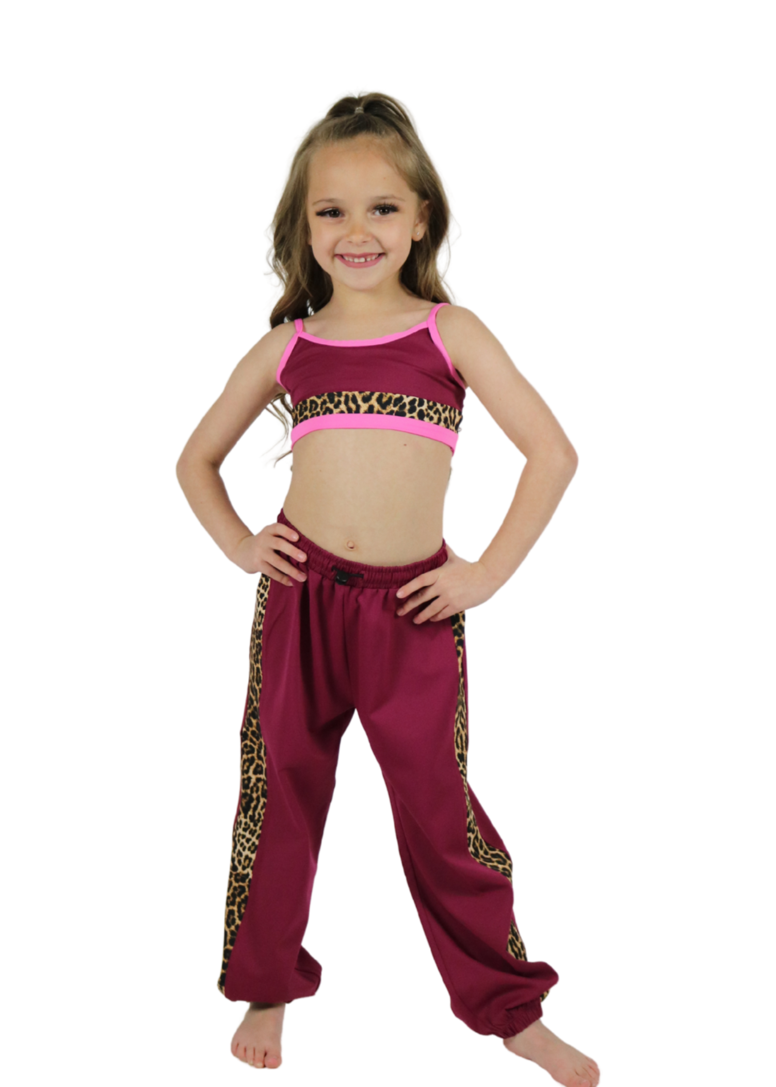 Young girl wearing a pink top and maroon pants with leopard print trim on a white background