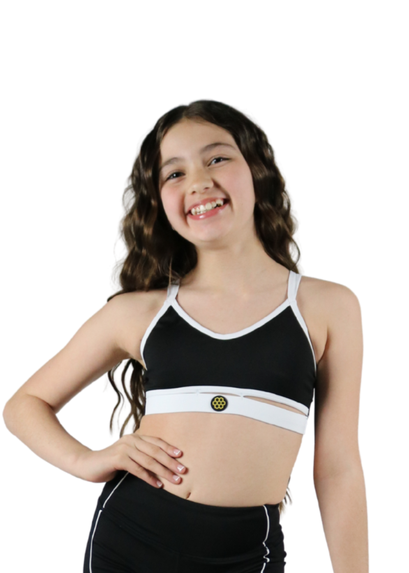 Young girl wearing a black sports bra and shorts set on a white background